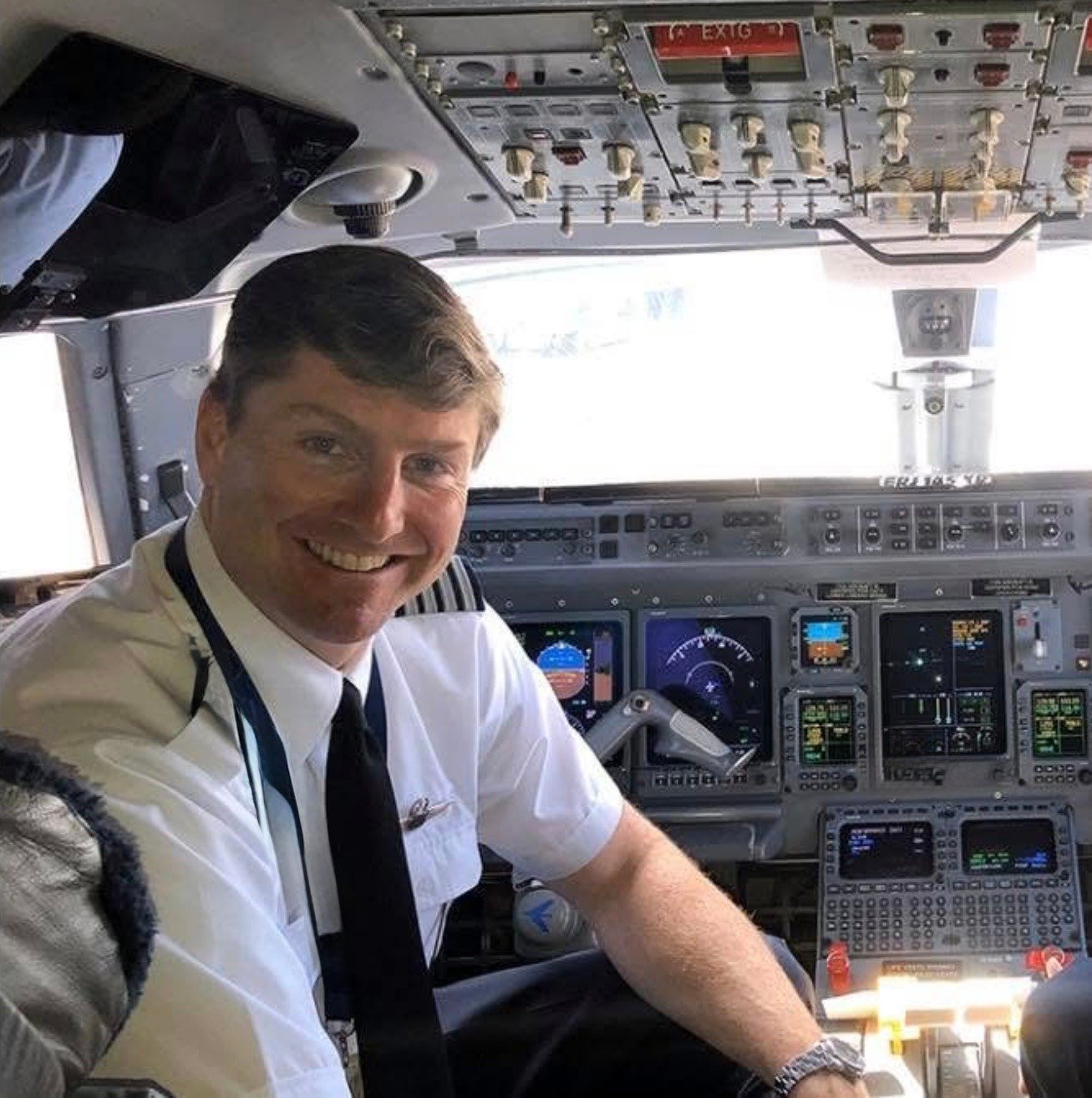 Smiling airline pilot sitting in the cockpit of a commercial airplane